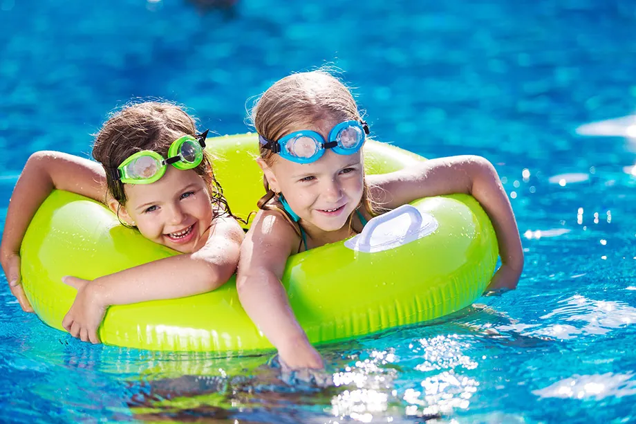 Dos niñas con goggles sobre un flotador en la alberca