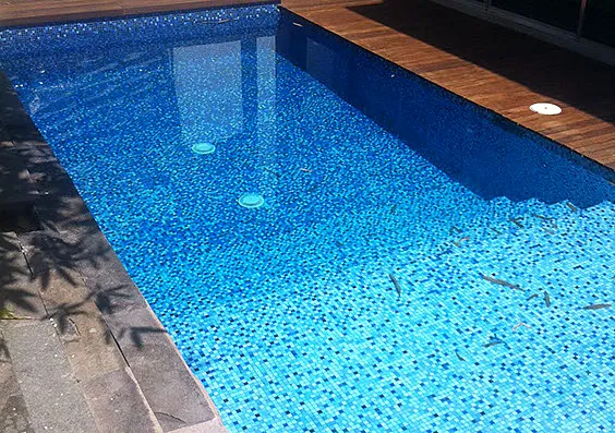 Alberca con mosaico azul y borde de madera
