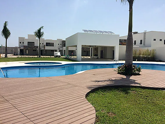 Alberca de club con deck de madera y palmera