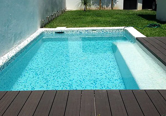 Alberca con mosaico claro y deck de madera oscura