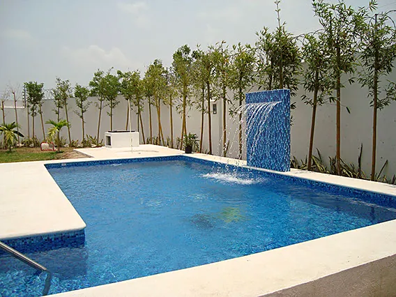 Alberca con cascada de acero y jardín
