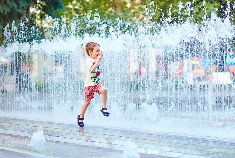 Niño corriendo entre los chorros de una fuente