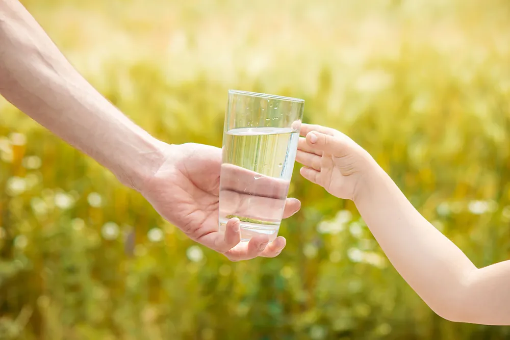 Mano sirviendo un vaso de agua limpia